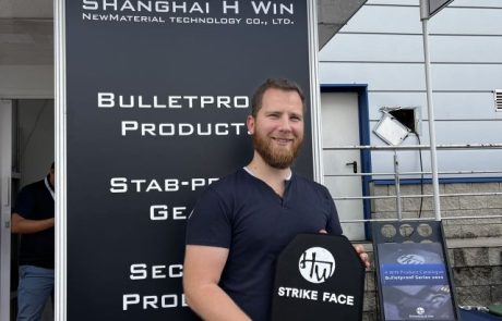 A man holding H Win's rifle plate in front of H Win's gate